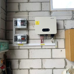 Adrian Stani WISTAY - Instalacja fotowoltaiczna wewnątrz budynku: inwerter Sofar Solar, rozdzielnice elektryczne na ścianie z białego bloczka, widoczne okablowanie i elementy zabezpieczeń.