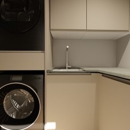 Chicc Interiors - Nowoczesna pralnia w beżowej tonacji: pralka i suszarka w zabudowie, minimalistyczny zlew z baterią, gładkie fronty szafek bez uchwytów, subtelne oświetlenie.