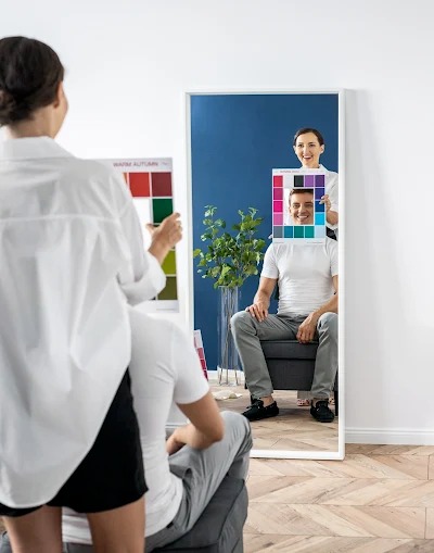 Konsultacja kolorystyczna: kobieta z paletą barw dobiera kolory do typu urody mężczyzny, odbicie w lustrze. Analiza kolorystyczna w jasnym wnętrzu.