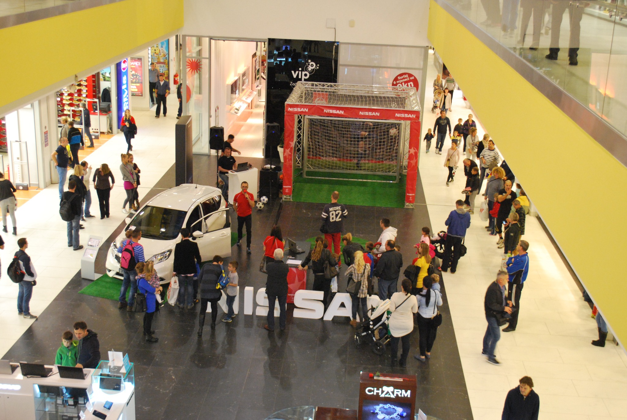 Event w galerii handlowej: biały samochód Nissan, bramka do piłki nożnej, tłum ludzi. Promocja marki w przestrzeni publicznej, widok z góry.