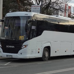 P.H.U. Tomasz Tymrakiewicz - Nowoczesny, biały autokar Scania z tablicą rejestracyjną WL 2773V, zaparkowany na tle miejskiego krajobrazu z elementami zieleni i budynków. Widoczny znak 'Turystyczny'.