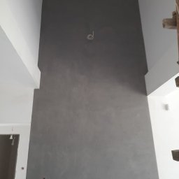 Zajdex - Szara ściana z efektem dekoracyjnym w surowym wnętrzu, widoczne kable i fragmenty konstrukcji, świeżo po malowaniu, z delikatną fakturą i minimalistycznym wykończeniem.