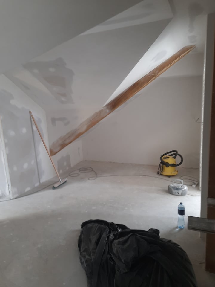 Poddasze po gipsowaniu ścian i sufitu w Teofilowie. Widoczny sprzęt budowlany, przygotowane do dalszych prac wykończeniowych. Ściany częściowo pomalowane.