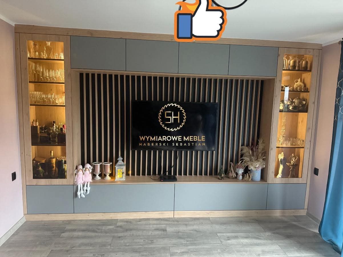 Szara zabudowa meblowa z podświetlanymi witrynami i lamelami za telewizorem. Dekoracje na półce. Nowoczesny design, jasne drewno, szare fronty.