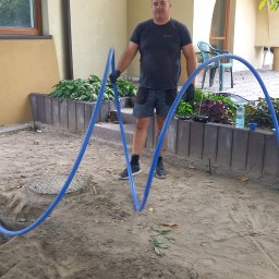 Arkoinstal - Instalator z niebieskimi rurami w Warszawie, przygotowuje się do ułożenia instalacji. Widoczne narzędzia i materiały budowlane.