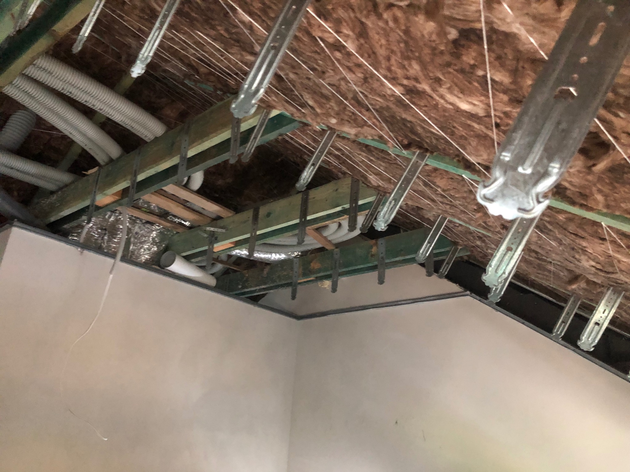 Montaż sufitu podwieszanego z instalacją w Nadarzynie. Widoczne profile, izolacja i rury wentylacyjne. Prace wykończeniowe w trakcie realizacji.