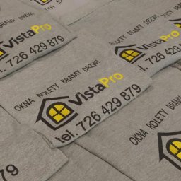PATI-HAFT MARZENNA POŁETEK - Szare koszulki z nadrukiem logo firmy VistaPro (okna, rolety, bramy, drzwi) w kolorach czarnym i żółtym, ułożone warstwami. Widoczne numery telefonów.