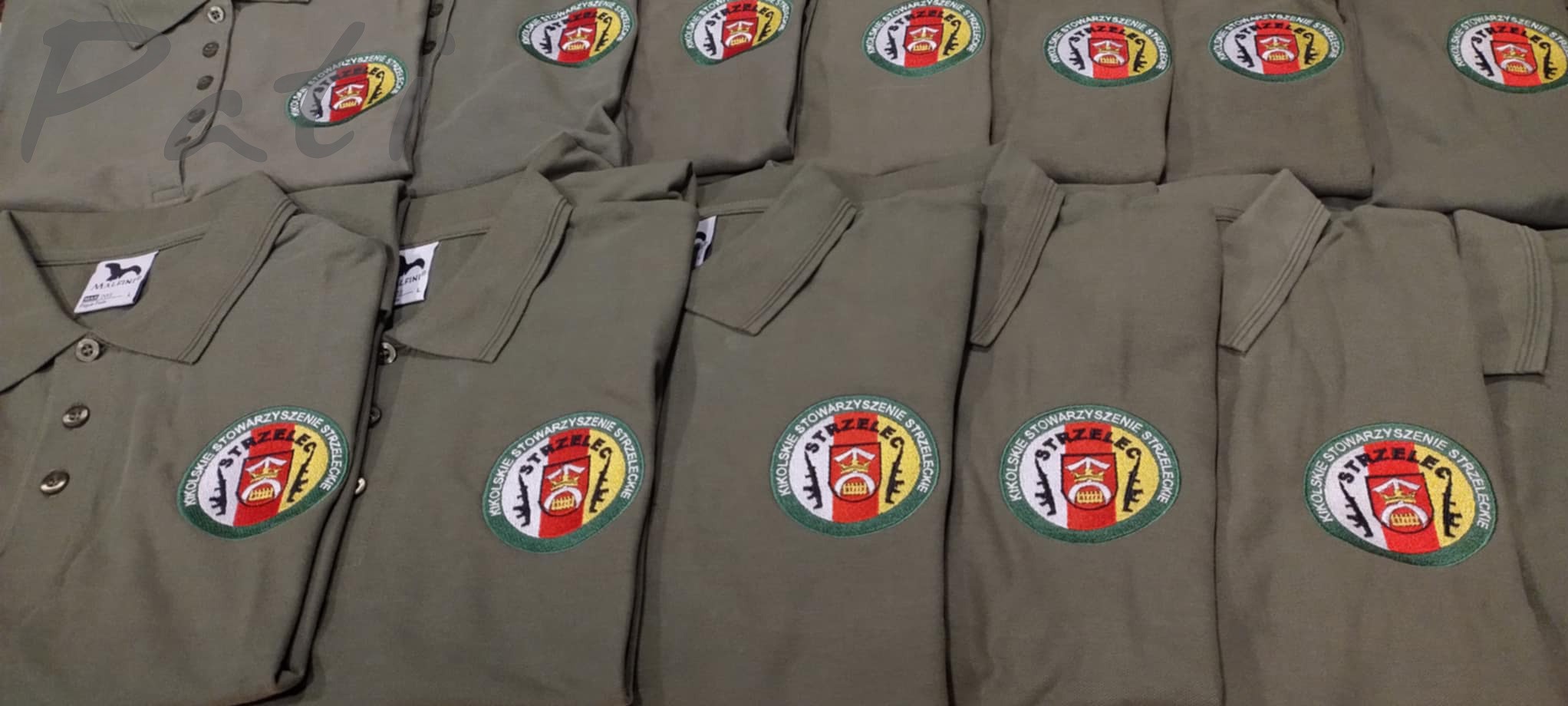Koszule polo khaki z haftowanym logo 'KIKOLSKIE STOWARZYSZENIE STRZELECKIE'. Widoczne detale haftu i układ koszul na płaskiej powierzchni.