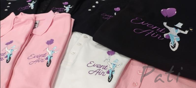 Różnokolorowe koszulki polo z haftowanym logo 'Event Air' i postacią na monocyklu z balonami, ułożone warstwowo. Widoczne detale haftu i różne kolory koszulek.