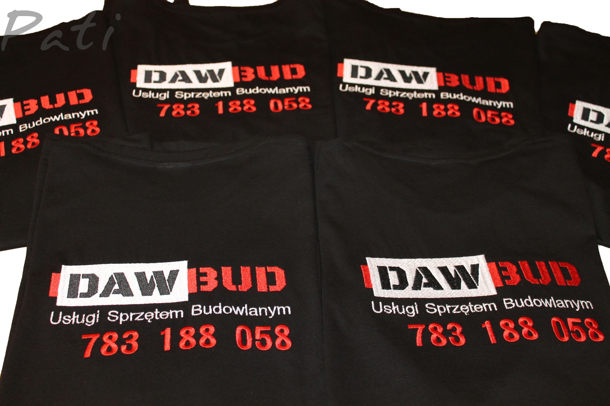 Czarna koszulka z haftowanym logo 'DAW BUD' i numerem telefonu w kolorze czerwonym. Widoczne detale haftu i układ koszulek.