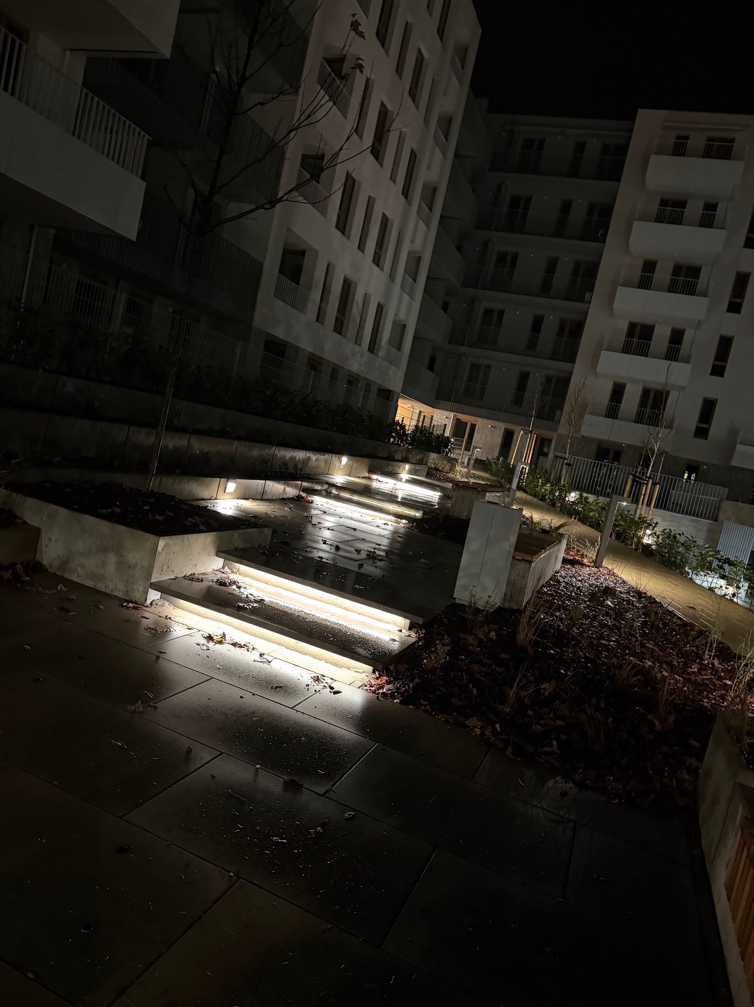 Nocne ujęcie schodów z podświetleniem LED w nowoczesnym osiedlu. Światła podkreślają architekturę, tworząc bezpieczne i estetyczne przejście.