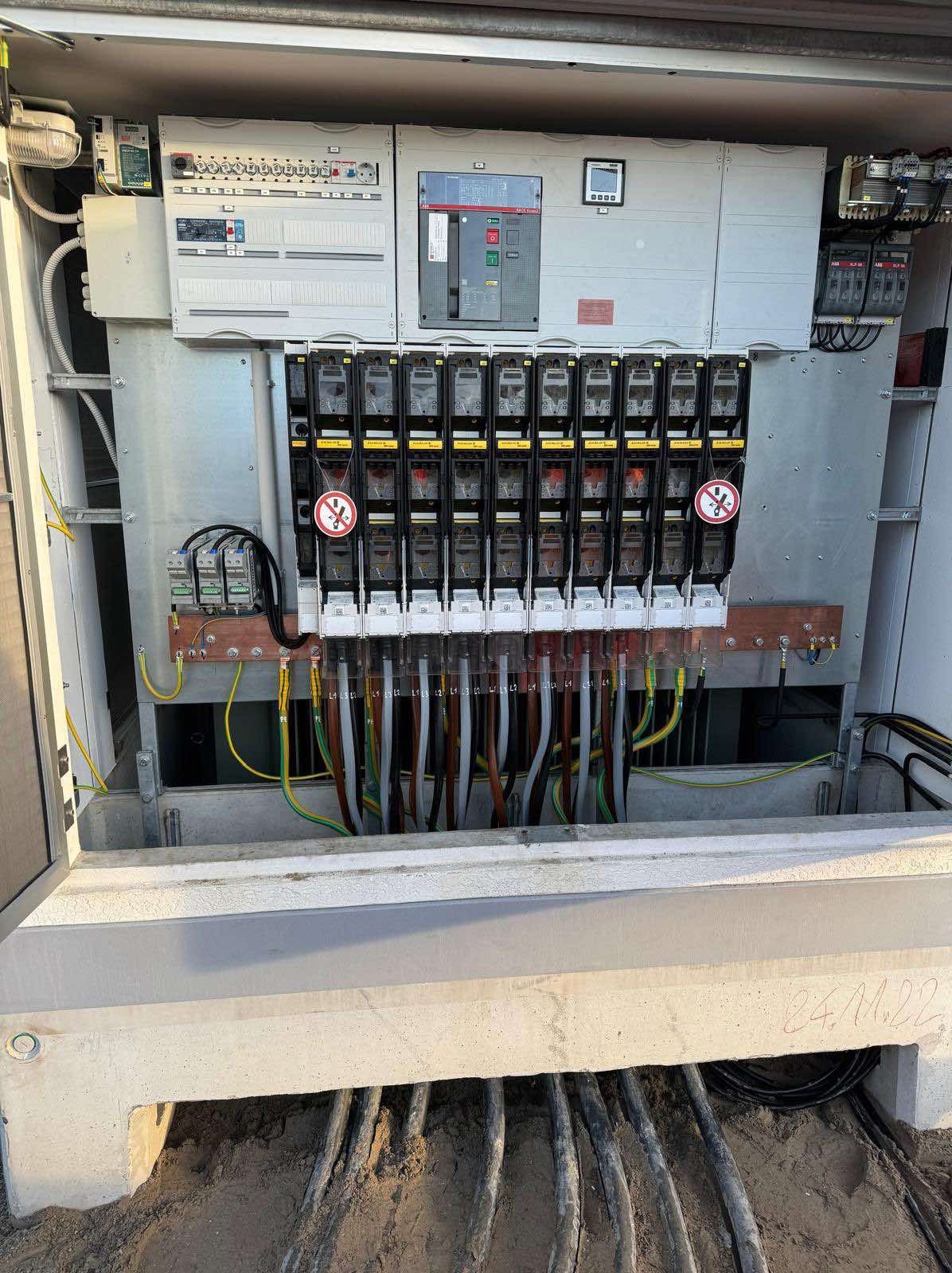 Rozdzielnica elektryczna z bezpiecznikami i okablowaniem w skrzynce betonowej. Instalacja wykonana we Wrocławiu. Widoczne oznaczenia i kable.