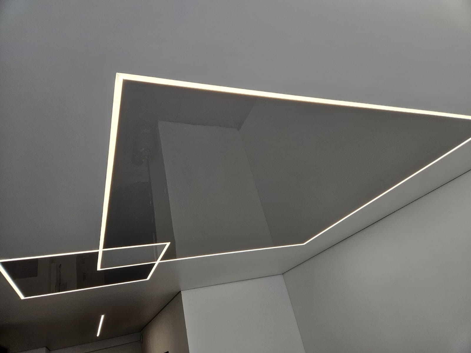 Nowoczesny sufit podwieszany z oświetleniem LED w kształcie geometrycznym. Minimalistyczny design, gładka powierzchnia, białe ściany. Wykończenie wnętrz.