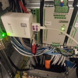 Sławomir Troszczynski - Szafa sterownicza z modułami zasilania Phoenix Contact Quint Power, adapterem Cellularline i okablowaniem. Widoczne złącza, przewody i oznaczenia na urządzeniach.