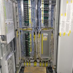 Sławomir Troszczynski - Rozbudowana szafa sterownicza z precyzyjnie ułożonymi kablami, modułami elektronicznymi i listwami zaciskowymi. Widoczne narzędzia elektryczne sugerują etap prac instalacyjnych.