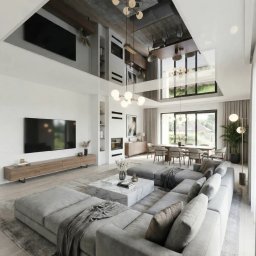 Przestronny, dwukondygnacyjny salon w nowoczesnym stylu industrialno-luksusowym. Wysoki sufit z odsłoniętymi elementami konstrukcyjnymi i betonem architektonicznym, przełamany dużymi przeszkleniami i antresolą z balustradą szklaną.