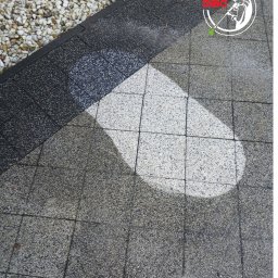 Mycie u Marchewy Michał Marchlewski - Fragment kostki brukowej po czyszczeniu, widoczna różnica w kolorze i czystości. Część kostki mokra, obok kamyczki ozdobne i logo firmy w prawym górnym rogu.