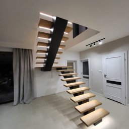 Kamil jonca - Nowoczesne schody drewniane z podświetleniem LED, wspornikowe stopnie i czarna konstrukcja nośna. Minimalistyczny design w jasnym wnętrzu.