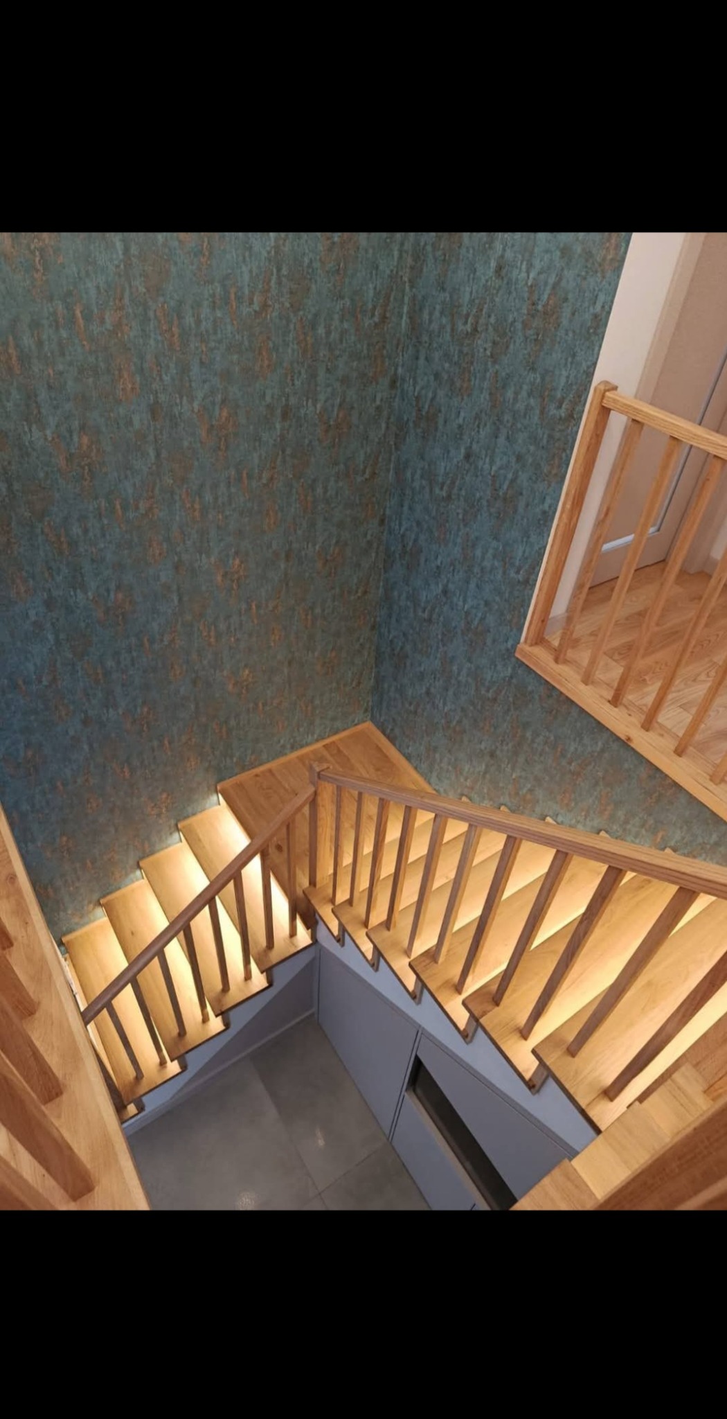 Nowoczesne schody z jasnego drewna z podświetleniem LED, widok z góry. Dekoracyjna ściana w tle. Minimalistyczny design i precyzyjne wykonanie.