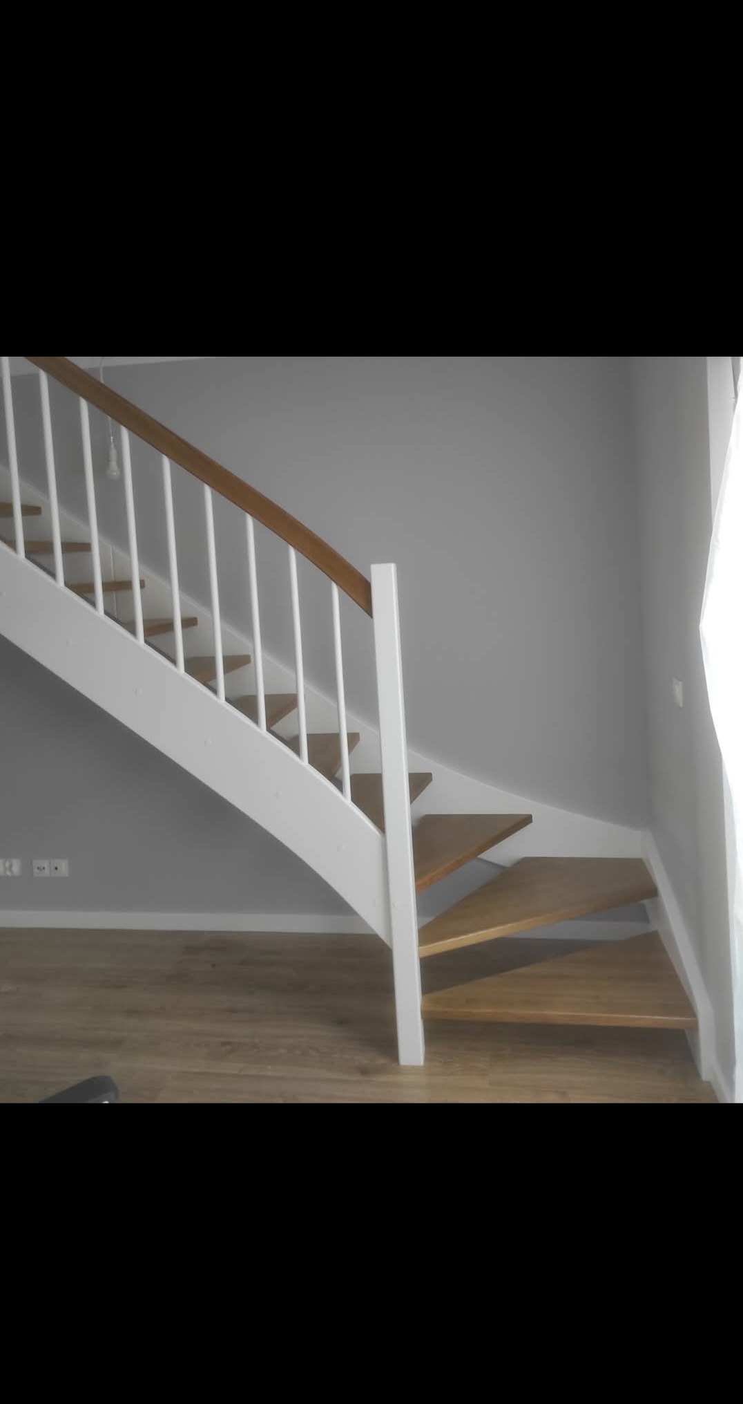 Jasne schody z drewnianymi stopniami i białą balustradą w nowoczesnym wnętrzu. Minimalistyczny design, naturalne światło, widok z dołu na górę.