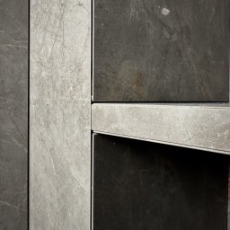 TARABUD - Szczegółowe ujęcie szarych płytek imitujących marmur, ułożonych w pionowe pasy z widocznymi fugami. Płytki w odcieniach szarości i grafitu, z delikatnymi żyłkami.