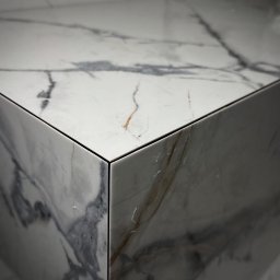 TARABUD - Detal narożnika wykończonego płytami z marmurowym wzorem. Precyzyjne łączenie płyt, widoczne subtelne żyłki i polerowana powierzchnia. Minimalistyczny design.