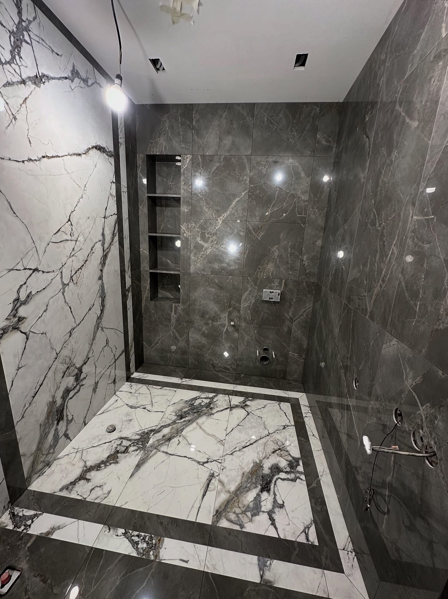 Strefa prysznicowa z gresu wielkoformatowego. Dopasowanie rysunku płytek oraz wykonanie nisz i siedziska.