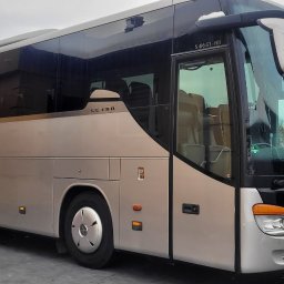 LenartTour.pl Przewóz Osób Paweł Lenart - Beżowy autokar Setra S 416 GT-HD na tle zimowego krajobrazu. Widoczne detale: logo, reflektory, tablica rejestracyjna. Ujęcie z boku, podkreślające długość pojazdu.