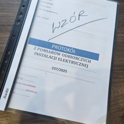 EFV WELPOL - Protokół z pomiarów odbiorczych instalacji elektrycznej w segregatorze, z widocznym napisem 'WZÓR' i danymi wykonawcy pomiarów.