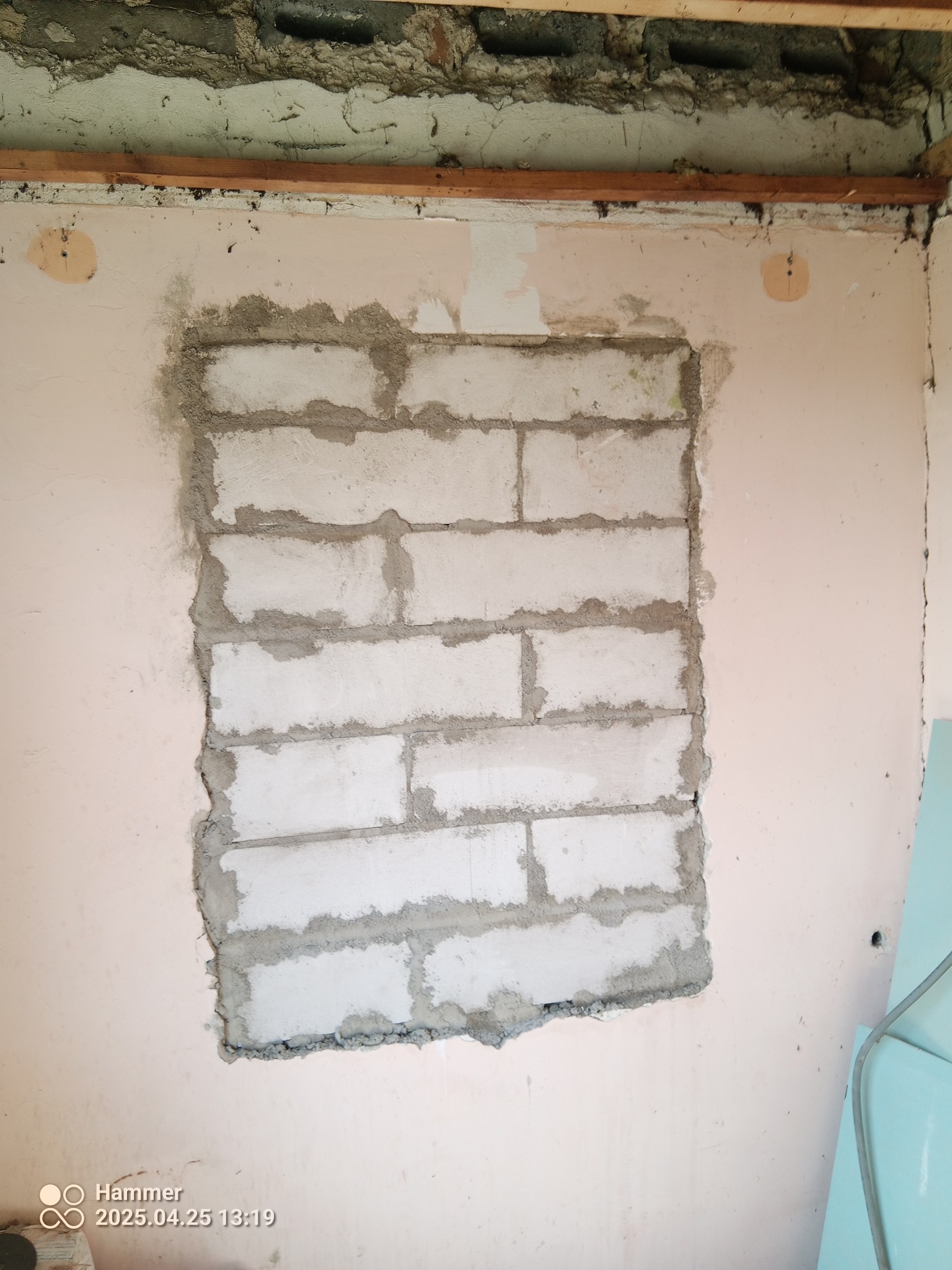 Murowanie otworu w ścianie z bloczków w Olszówce. Widoczne surowe wykończenie i fragment ściany przed dalszymi pracami. Bloki połączone zaprawą.