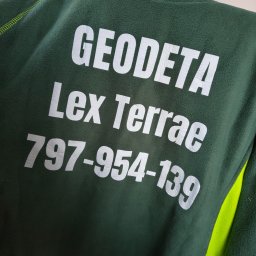 Lex Terrae Łukasz Szajewski - Zielona bluza polarowa z nadrukowanym białym napisem 'Geodeta Lex Terrae 797-954-139', widoczna część rękawa w kolorze jaskrawej zieleni.