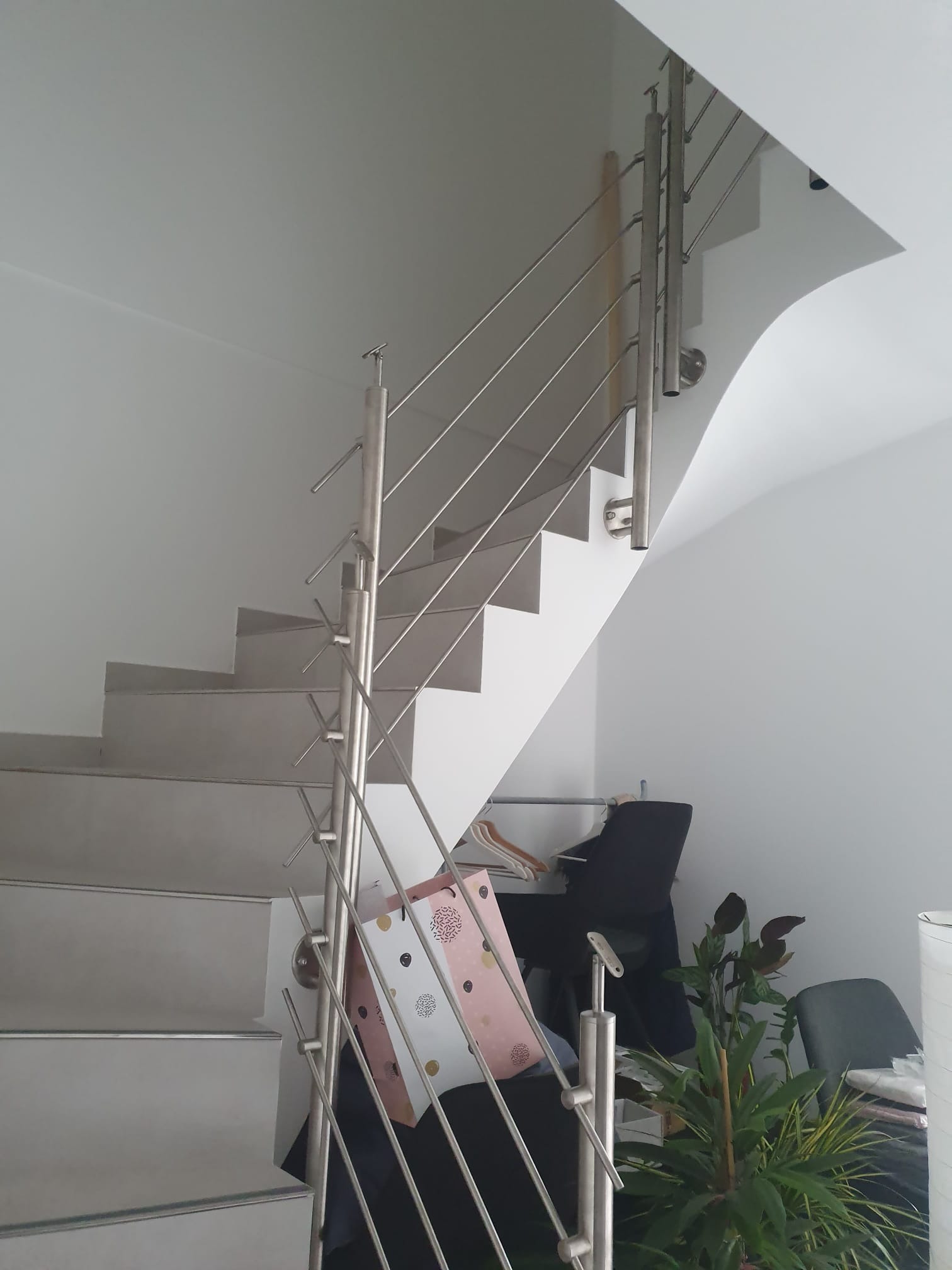 Schody z metalową balustradą w jasnym wnętrzu. Widoczne detale wykończenia. Realizacja w Gryfinie. Minimalistyczny design.