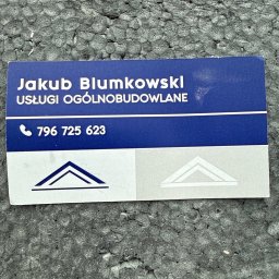 Maxbud Jakub Blumkowski - Wizytówka Jakuba Blumkowskiego, usługi ogólnobudowlane, numer telefonu na tle szarej, chropowatej powierzchni, prawdopodobnie styropianu.