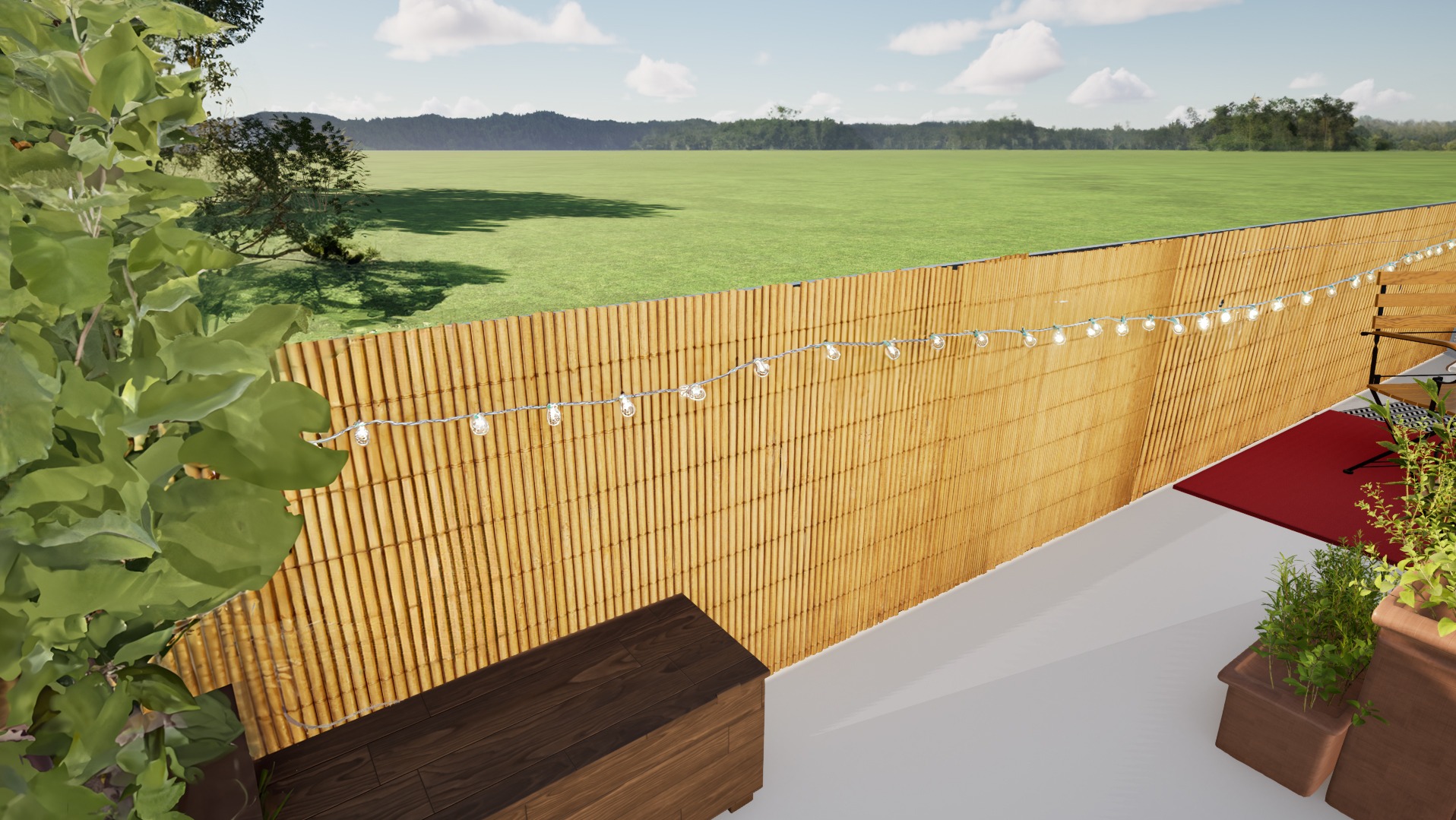 Bambusowe ogrodzenie z lampkami na tle zielonego pola i nieba. Na pierwszym planie rośliny w donicach i drewniana skrzynia. Widok z góry.