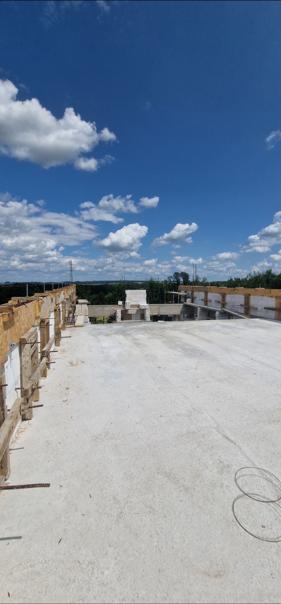 Wylany strop z szalunkiem drewnianym i widokiem na błękitne niebo z chmurami. Etap budowy domu z betonu.