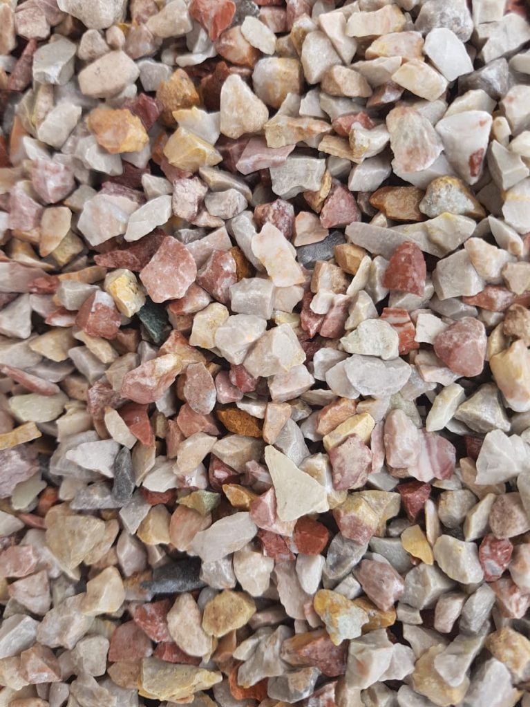 Drobne, nieregularne kamienie w odcieniach bieli, beżu i czerwieni, tworzące teksturę. Widoczne różnice w kształcie i kolorze poszczególnych elementów.