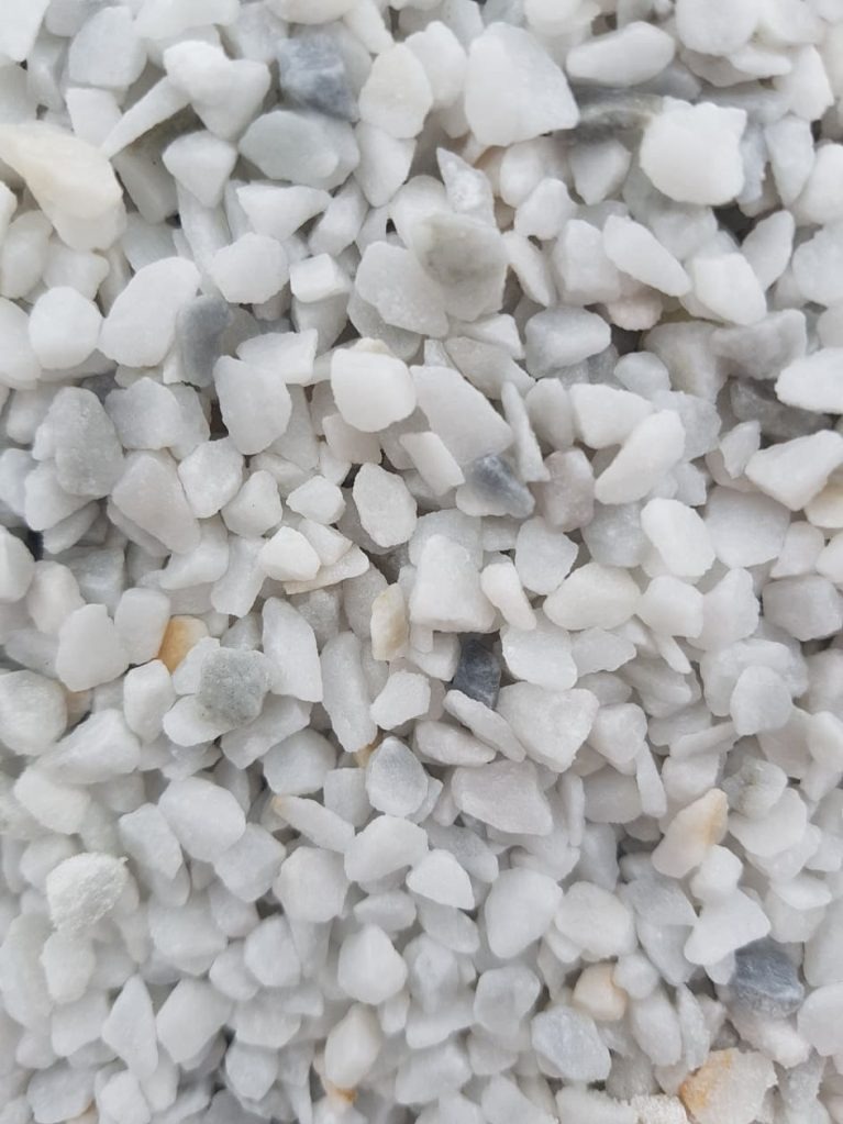 Białe, drobne kamyczki marmurowe o nieregularnych kształtach, tworzące gęstą teksturę. Delikatne szare i beżowe akcenty dodają głębi.