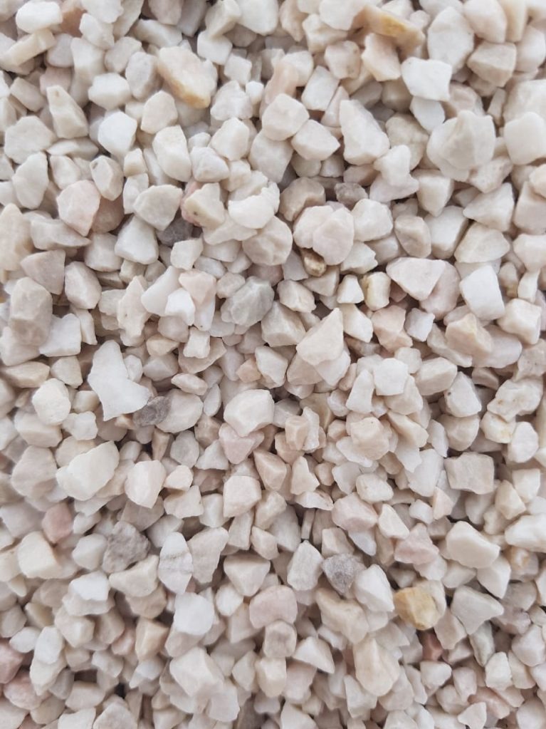 Beżowo-biały grys marmurowy, drobne kamyczki o nieregularnych kształtach, wypełniające całą powierzchnię kadru, z delikatnymi przebarwieniami.