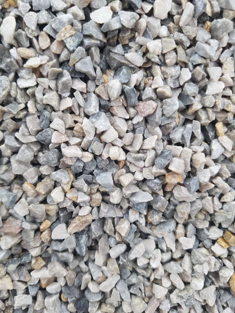 Szary żwir kamienny o zróżnicowanej granulacji, wypełniający całą powierzchnię kadru. Widoczne odcienie bieli, szarości i beżu. Materiał budowlany.