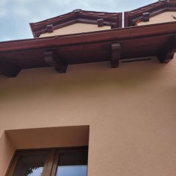 Sebastian Jan - Elewacja domu jednorodzinnego w Margoninie, z widocznym oknem i drewnianą podbitką dachową. Jasna kolorystyka ścian i detali architektonicznych.