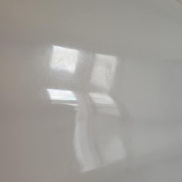 Sebastian Jan - Błyszcząca, jasnoszara powierzchnia z refleksami okien. Widoczne delikatne smugi i niedoskonałości, sugerujące świeżo pomalowaną ścianę lub sufit.