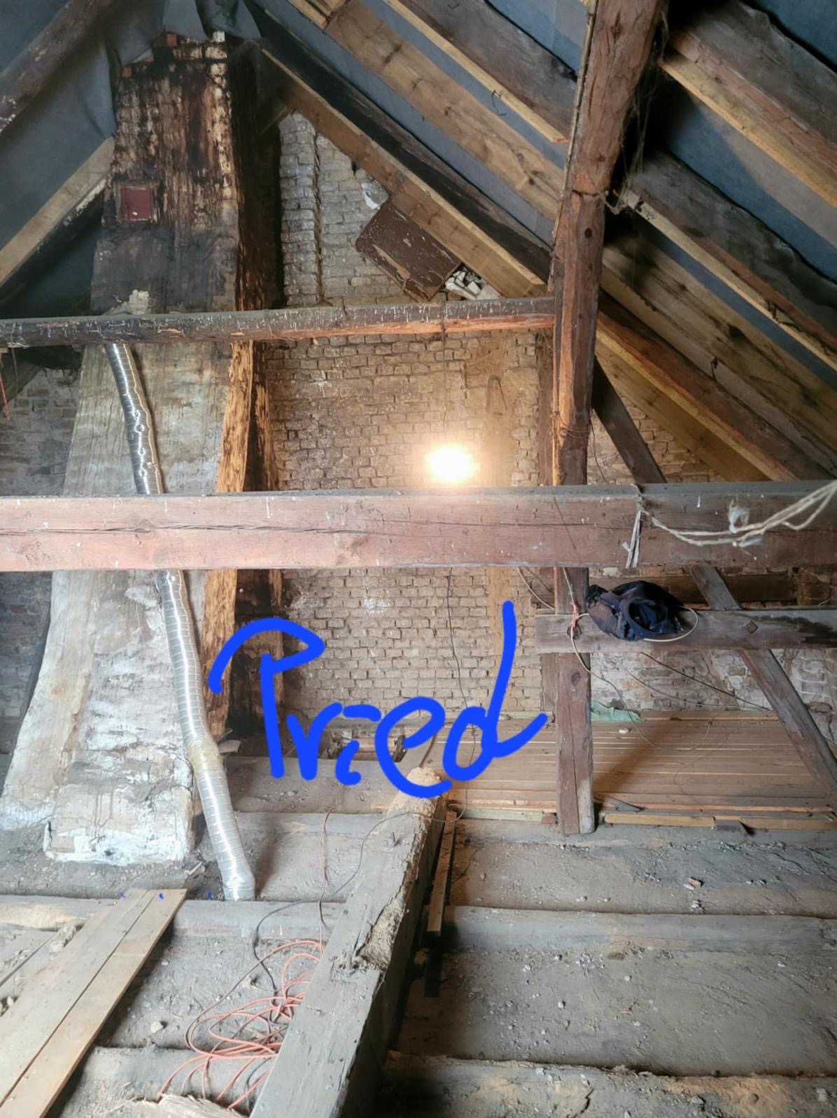 Stare poddasze z odsłoniętą cegłą i drewnianą konstrukcją dachu przed remontem. Widoczne elementy instalacji i fragmenty podłogi. Ujęcie z dołu.