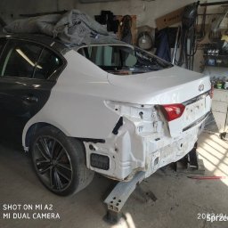 Majcar - Auto po naprawie blacharskiej, przygotowane do lakierowania. Widoczne szpachlowane elementy karoserii i podkład. Warsztat z narzędziami w tle.