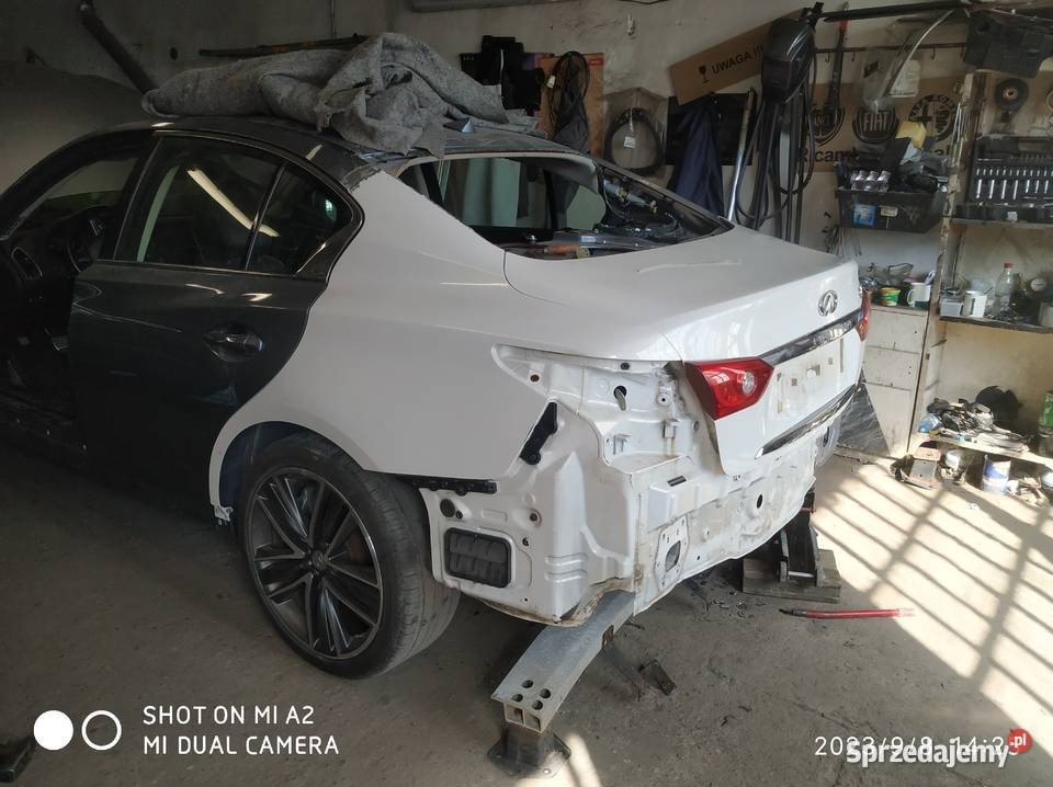 Auto po naprawie blacharskiej, przygotowane do lakierowania. Widoczne szpachlowane elementy karoserii i podkład. Warsztat z narzędziami w tle.