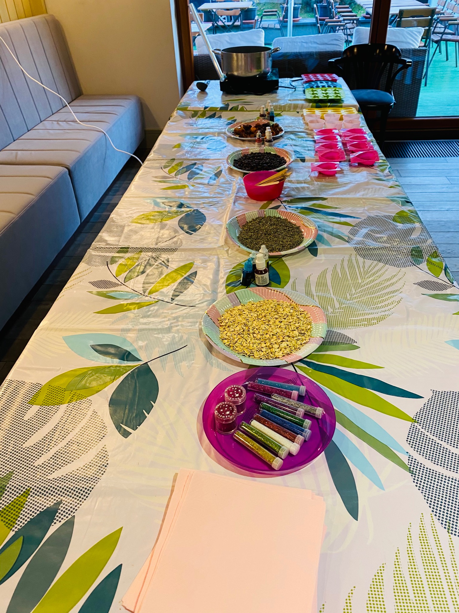 Stół z materiałami do warsztatów kreatywnych: barwniki, brokaty, foremki, miseczki z ziarnami i płatkami. Przygotowanie do zajęć plastycznych dla dzieci.