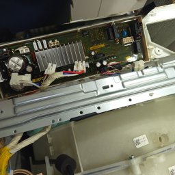 ELEKTRO AL SPÓŁKA Z OGRANICZONĄ ODPOWIEDZIALNOŚCIĄ - Otwarta obudowa pralki z widoczną płytą sterującą, elementami elektronicznymi i przewodami. Widoczne kondensatory, radiatory i złącza. Detal naprawy sprzętu AGD.