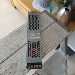 Elektro AL - Zasilacz modułowy 360W marki Ecolight, model EC61763, leżący na aluminiowej drabinie. Widoczne przewody zasilające i elementy elektroniczne przez otwory wentylacyjne.