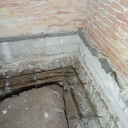 Marian Moskwa - Wykopany rów z widocznym zbrojeniem i fragmentem ceglanej ściany. Przygotowanie do wylania fundamentów, widok z góry.