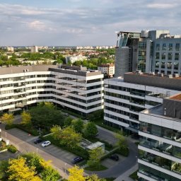Snapium - Kompleks biurowców z zielonymi dachami i parkingiem, widok z góry w słoneczny dzień. Nowoczesna architektura w otoczeniu zieleni miejskiej.