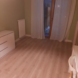 Oleksandr Partala - Pusty pokój po remoncie: świeżo pomalowane ściany w odcieniach zieleni, jasna podłoga, białe meble i okno z białymi zasłonami. Widok na zewnątrz.